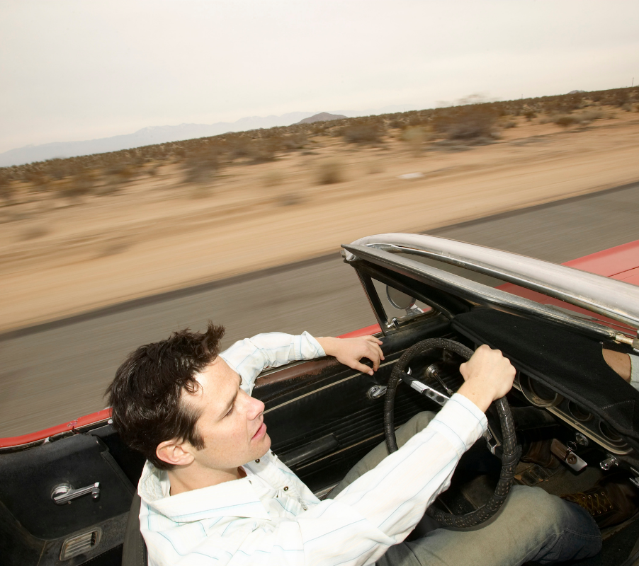 Man driving convertible through Arizona desert, highlighting summer car service needs at Airpark Auto Clinic Man driving convertible through Arizona desert, highlighting summer car service needs at Airpark Auto Clinic